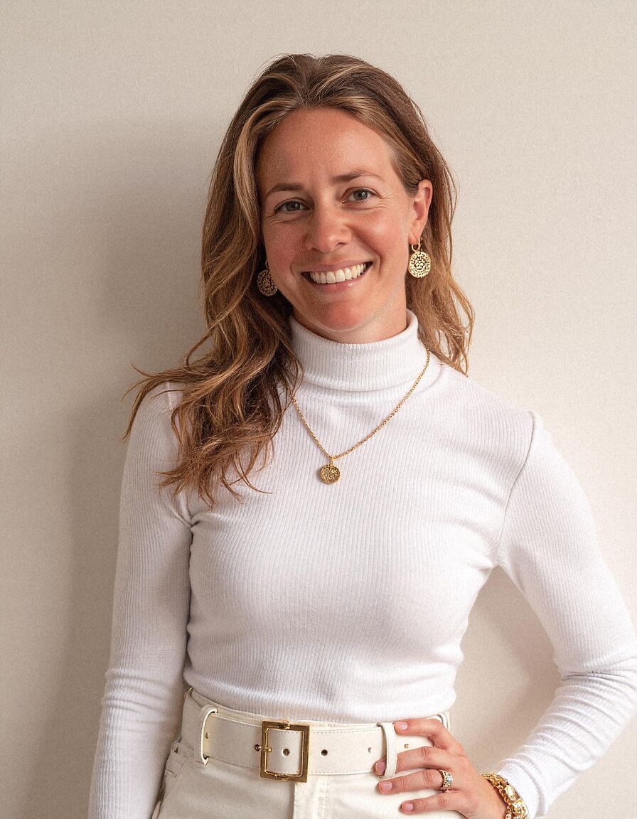 AI headshot of Hannah: plain wall, white roll-neck and gold necklace