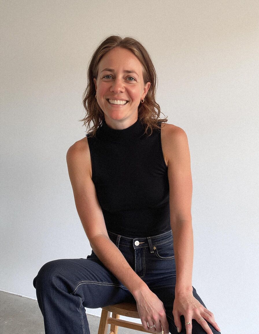 AI headshot of Hannah: studio, on a stool, black sleeveless top and jeans