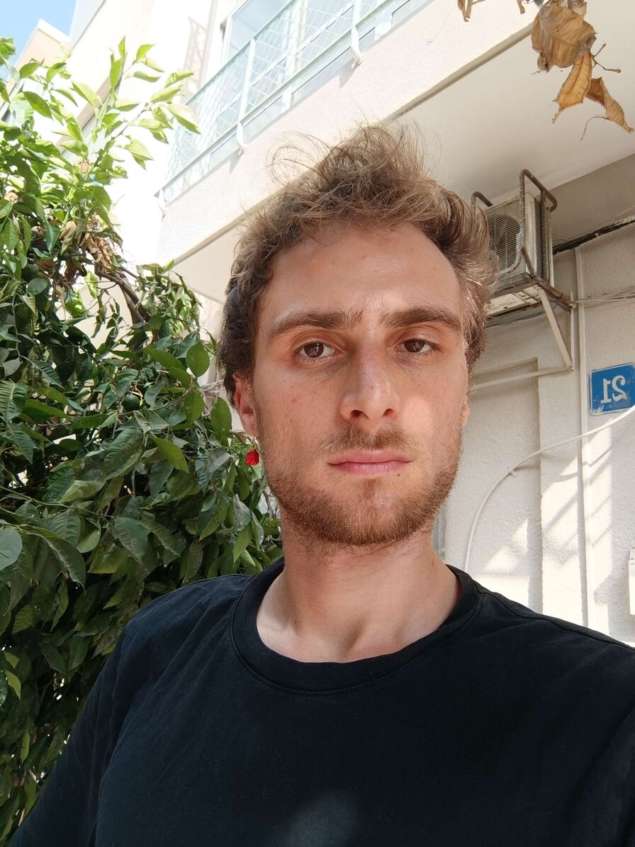 Theo's own selfie: selfie outdoors by a lemon tree in a black t-shirt